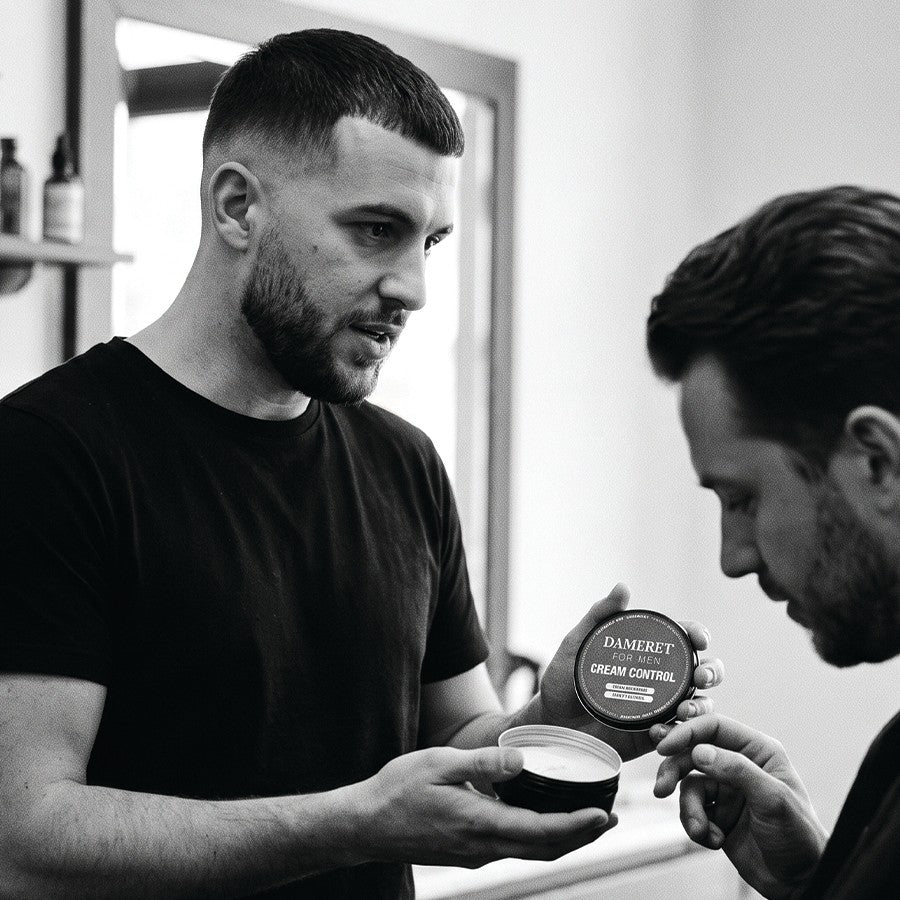 Barbier présentant la crème coiffante CREAM CONTROL DAMERET à un client