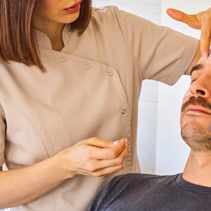 Esthéticienne réalisant un soin du visage sur un homme