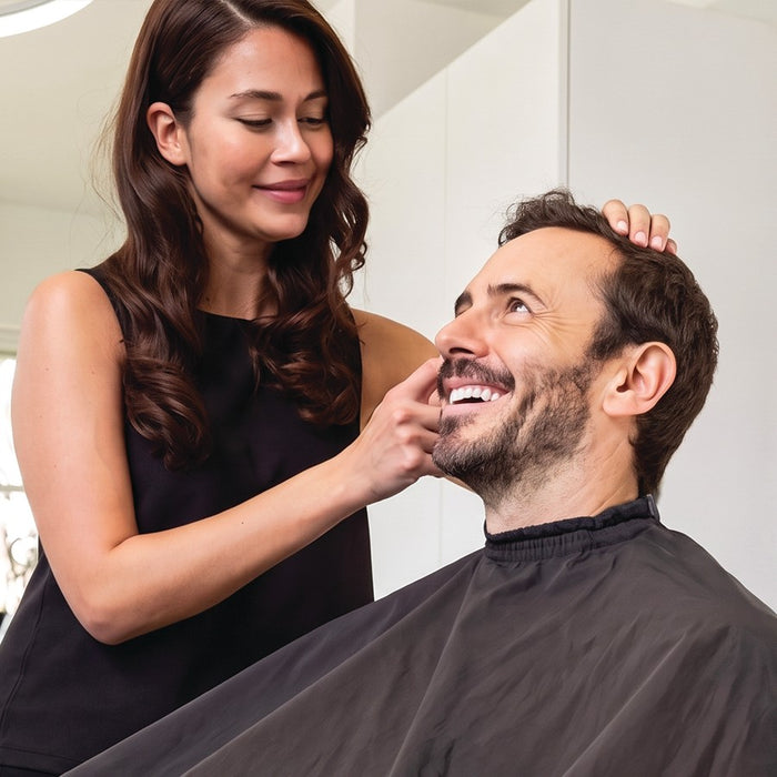 Coiffeuse et client homme souriant au fauteuil de coiffure